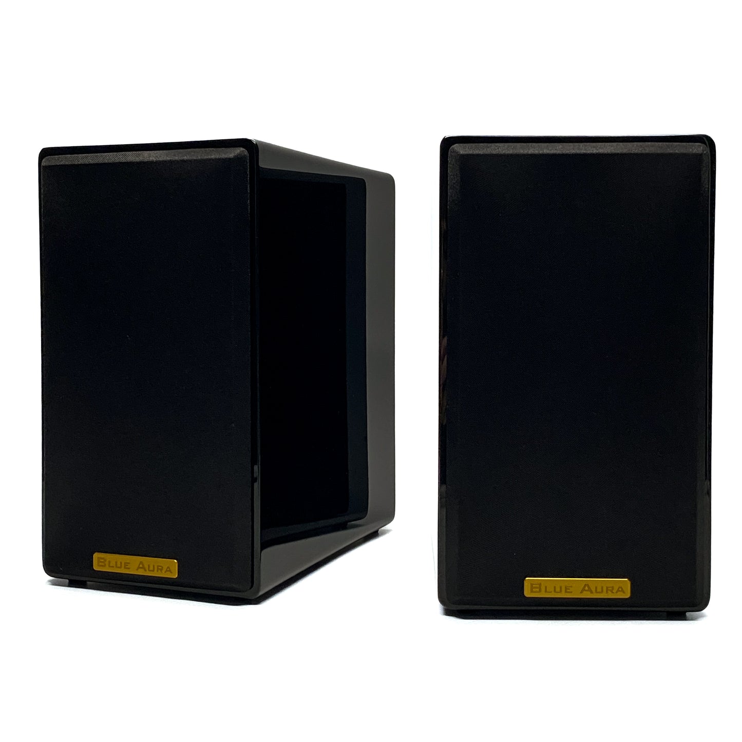 Official studio shot of a pair of Blue Aura AT700 compact bookshelf speakers with their black fabric protective grilles, showcasing the elegant gold metallic brand badges and high-gloss piano black finish.