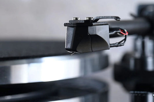 Macro close-up view of the official black phono cartridge and bare stylus assembly mounted on the straight tonearm of the Blue Aura Blackline PG2 turntable.