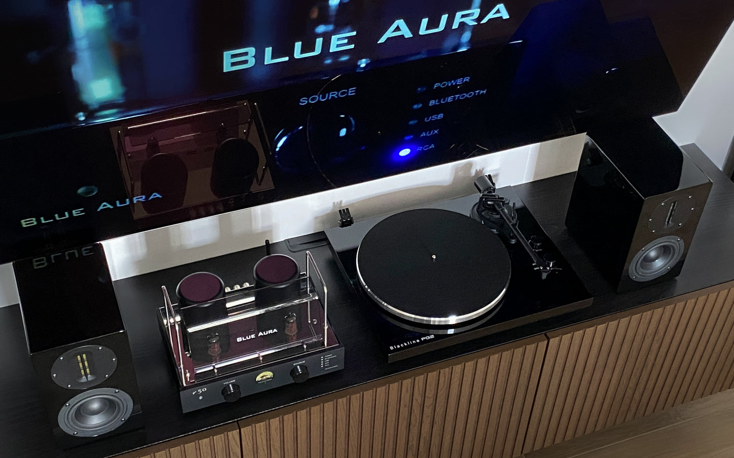 High-angle front view of the complete Blue Aura Soul System Black Hi-Fi setup on a TV cabinet, showing the turntable without its clear dust cover.