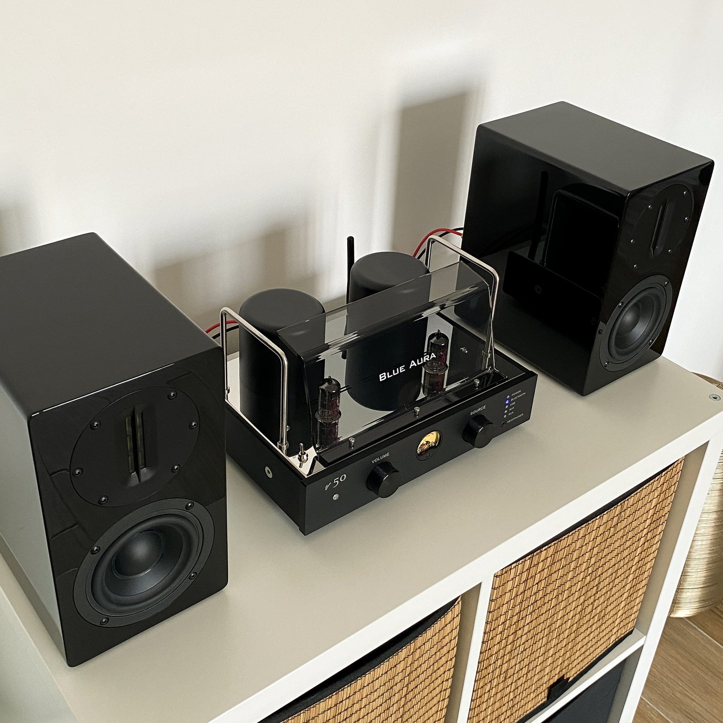 Close-up top-down view of the v50 amplifier and black AT700 speakers from the Blue Aura stereo system.