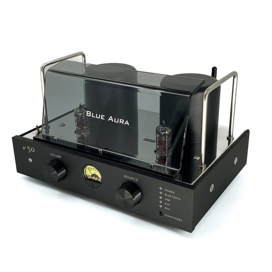 Official high-angle three-quarter studio view of the Blue Aura v50 hybrid valve amplifier at rest, highlighting its sleek front panel with dual black aluminium control knobs, circular VU meter, and protective plexiglas tube guard.