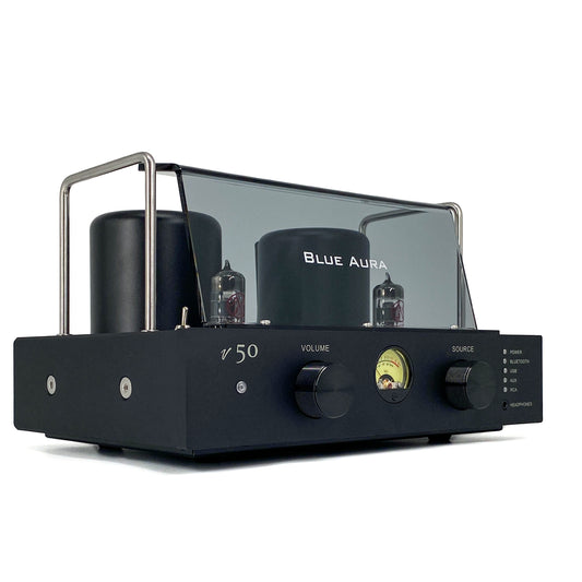 Official low-angle right three-quarter studio shot of the Blue Aura v50 hybrid valve amplifier at rest, showcasing its sleek front panel with dual black aluminium control knobs, circular VU meter, and protective plexiglas tube guard.