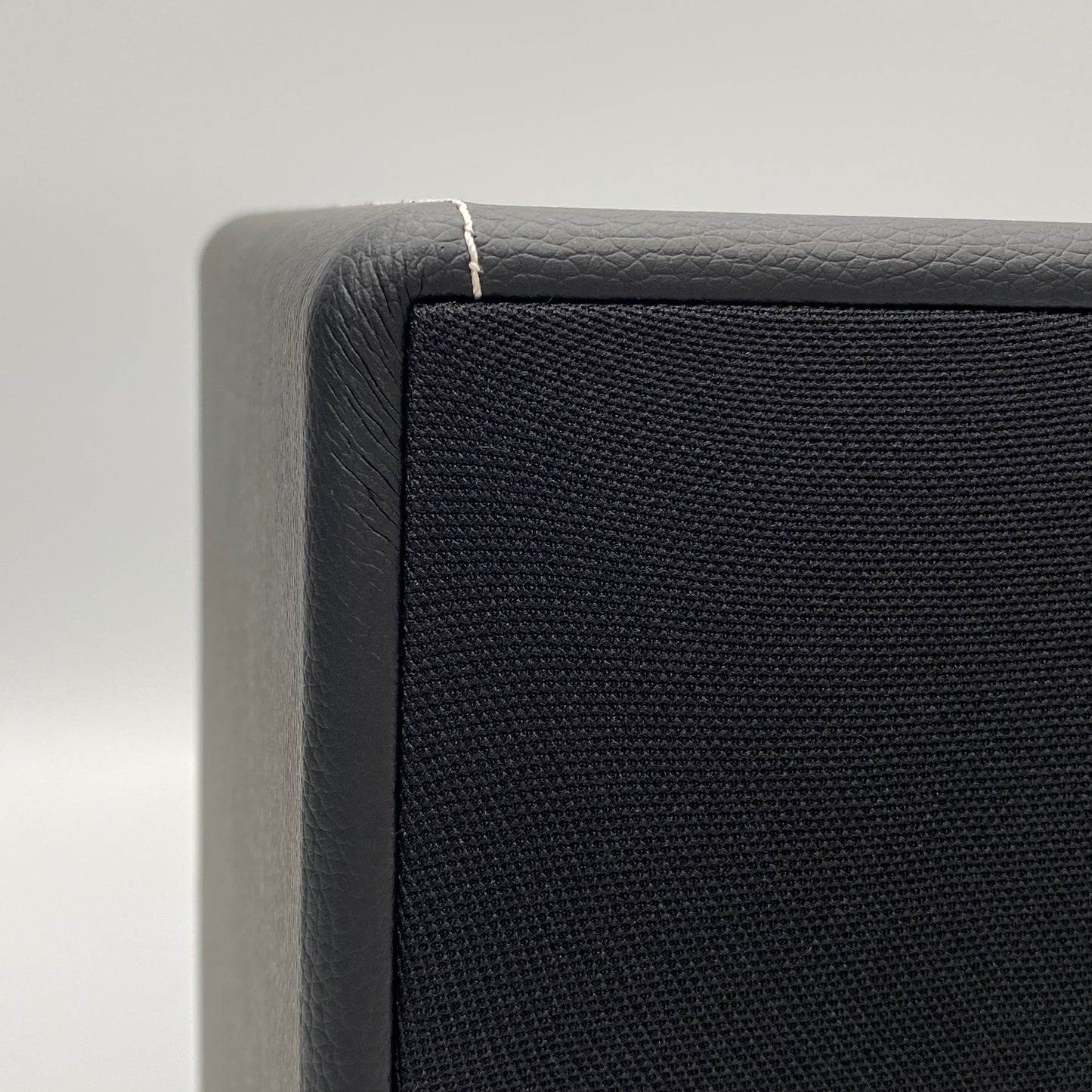 Official macro close-up view highlighting the premium stitching and textured black leatherette finish on the corner of the X-Sub subwoofer.