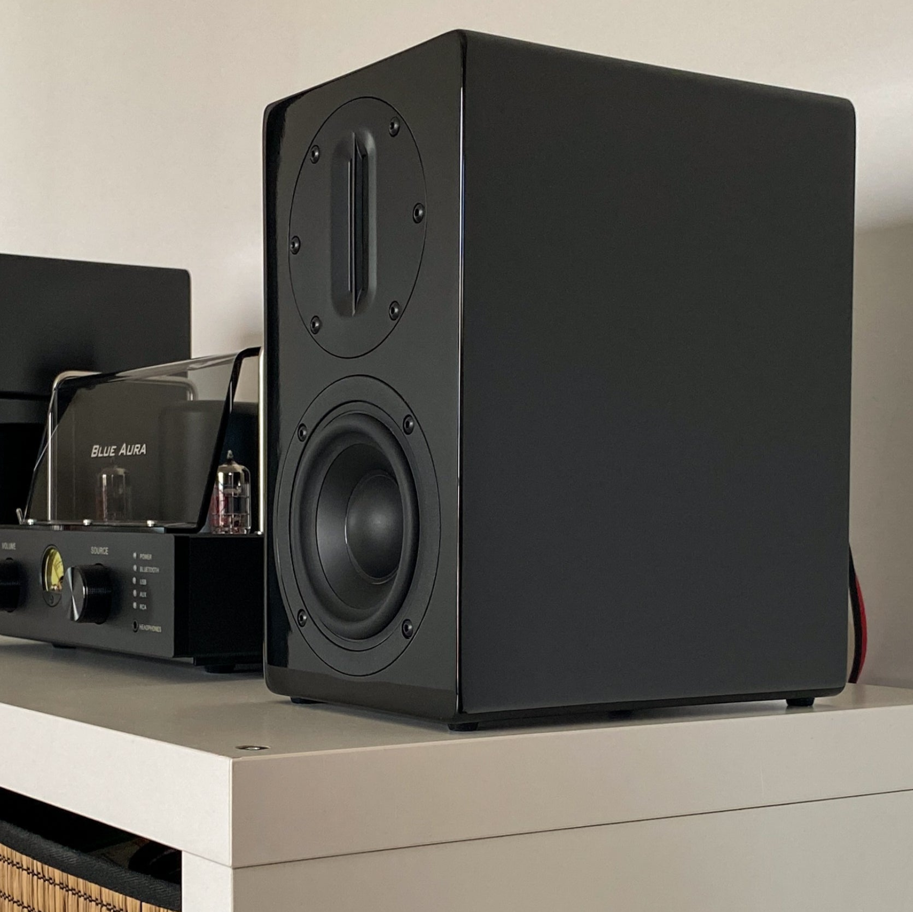 Close-up of the Blue Aura AT700 black right speaker next to the v50 hybrid amplifier.