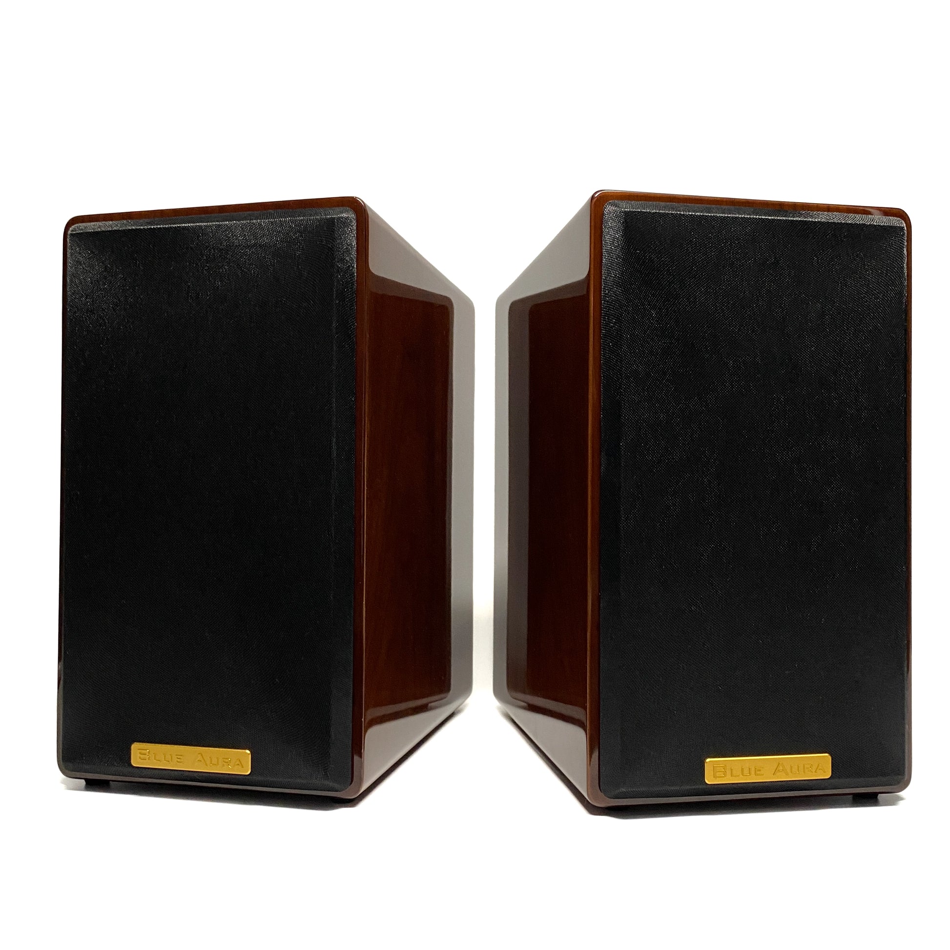 Balanced straight front studio view of the pair of Blue Aura AT700 compact bookshelf speakers, showcasing the stunning mirror-like reflection on their premium lacquer Walnut finish with the fabric grilles on.