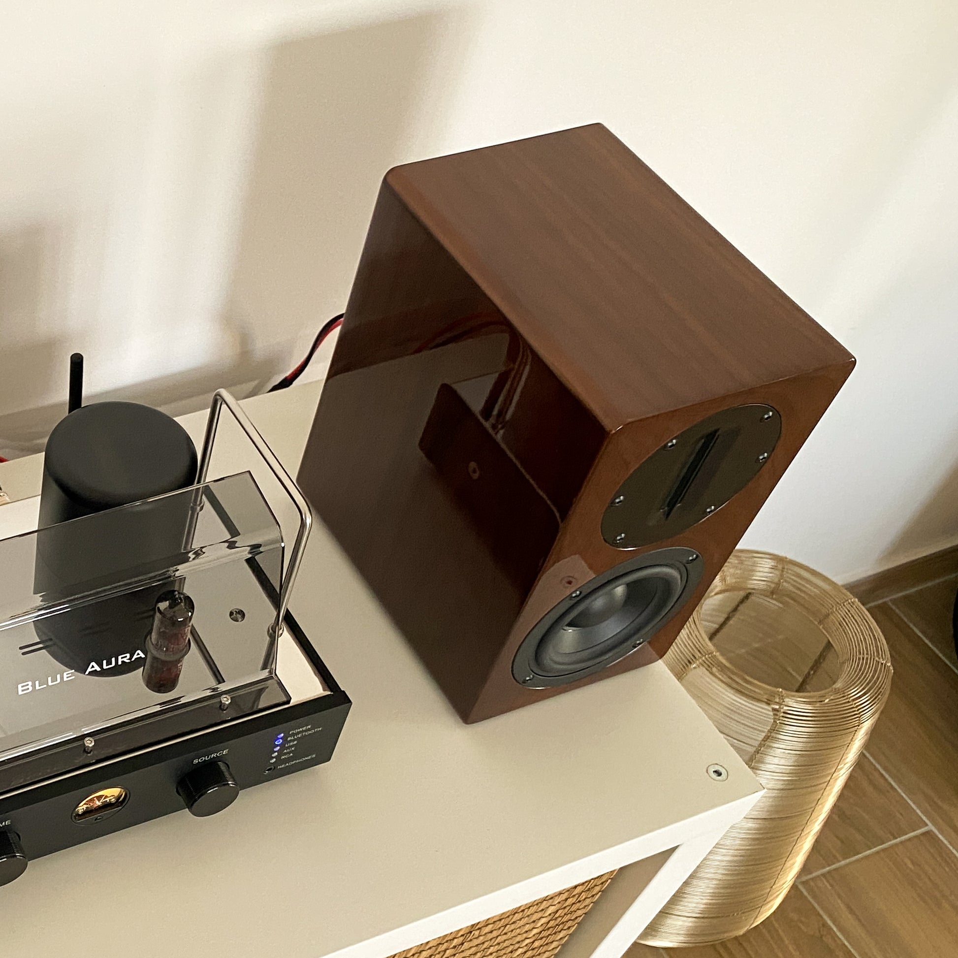High-angle view of the Walnut right AT700 speaker without front grille, positioned next to the v50 amplifier.