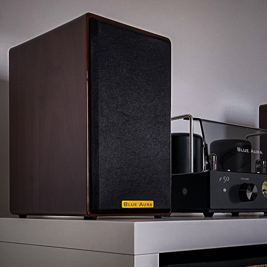 Close-up of the Blue Aura AT700 speaker in walnut finish with front grille on.