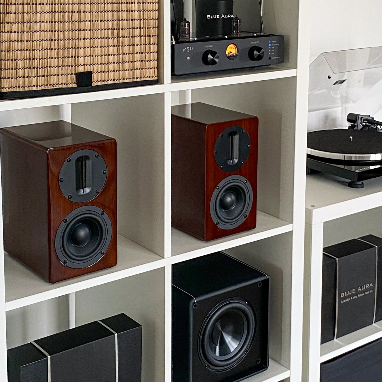 Pair of Blue Aura AT700 speakers in walnut finish placed inside a white bookshelf.