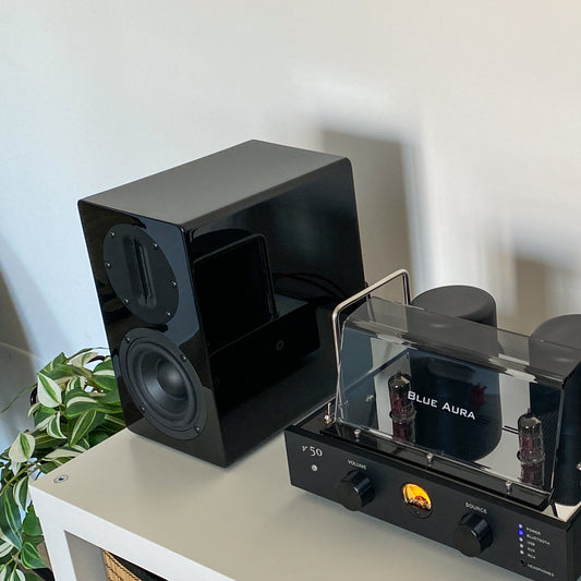 Detail of the high-gloss finish on the black AT700 speaker reflecting the v50 amplifier.