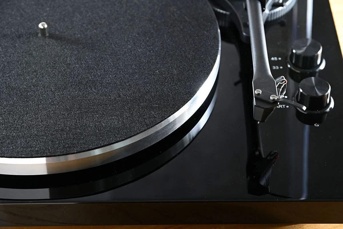 Official macro close-up view of the Blue Aura Blackline PG2 turntable, showcasing the edge of the aluminium platter with its black felt slipmat and the premium high-gloss black plinth.