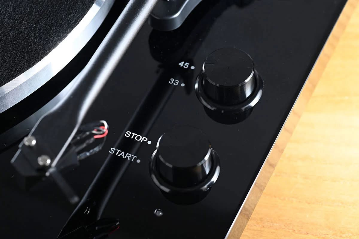 Official macro close-up view focusing on the 33/45 RPM speed selector and the start-stop motor control knobs on the high-gloss black plinth of the Blackline PG2 turntable.