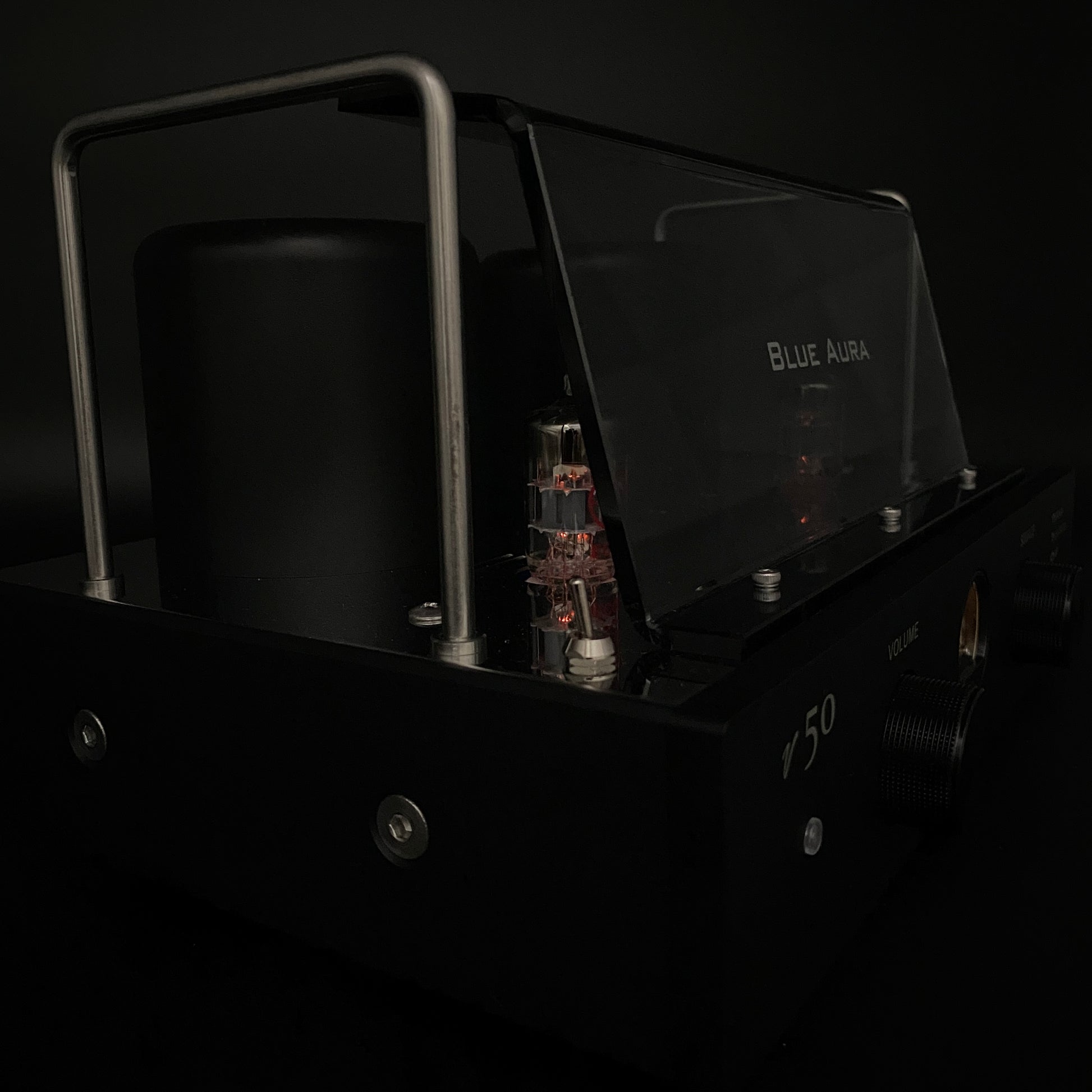 Close-up night view of the Blue Aura v50 amplifier focusing on the warm red glow of its operating valves in the dark.