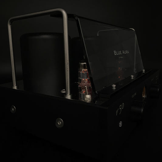 Close-up night view of the Blue Aura v50 amplifier focusing on the warm red glow of its operating valves in the dark.