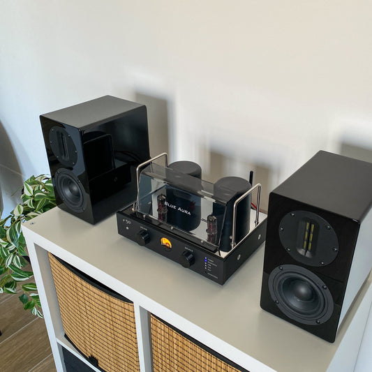 Top-down view of the v50 amplifier and black AT700 speakers from the Blue Aura stereo system.