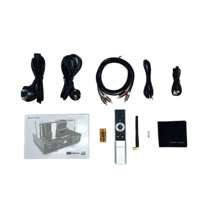 Flat lay studio view of the official setup items included with the Blue Aura v50 hybrid amplifier, featuring the user manual, brushed aluminium remote control, power cables, RCA cords, Bluetooth antenna, and microfibre cleaning cloth.