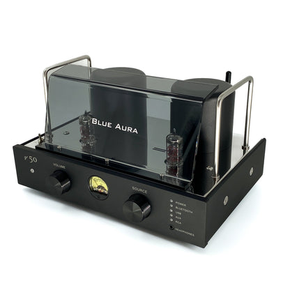 Official high-angle three-quarter studio view of the Blue Aura v50 hybrid valve amplifier at rest, highlighting its sleek front panel with dual black aluminium control knobs, circular VU meter, and protective plexiglas tube guard.