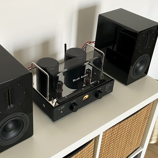 Blue Aura v50 valve amplifier turned on and placed on a white shelf.