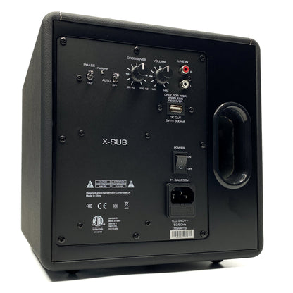 Three-quarter rear studio view of the Blue Aura X-Sub active subwoofer, showcasing its vertical bass reflex port, amplifier backplate, and premium black leatherette cabinet.
